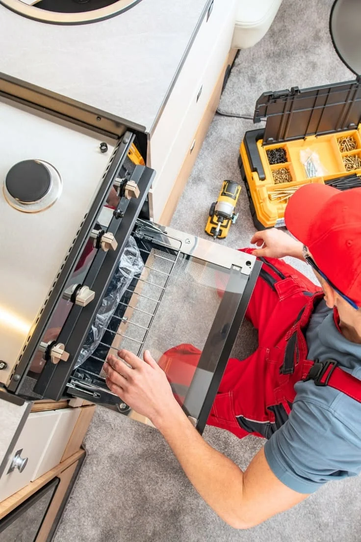 Technician inspecting an open oven beside a service toolbox